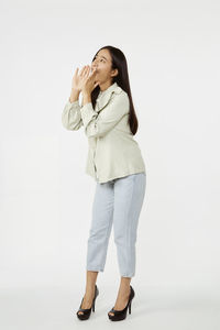 Young woman looking away while standing against white background