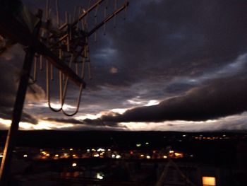 Low angle view of illuminated power lines against cloudy sky