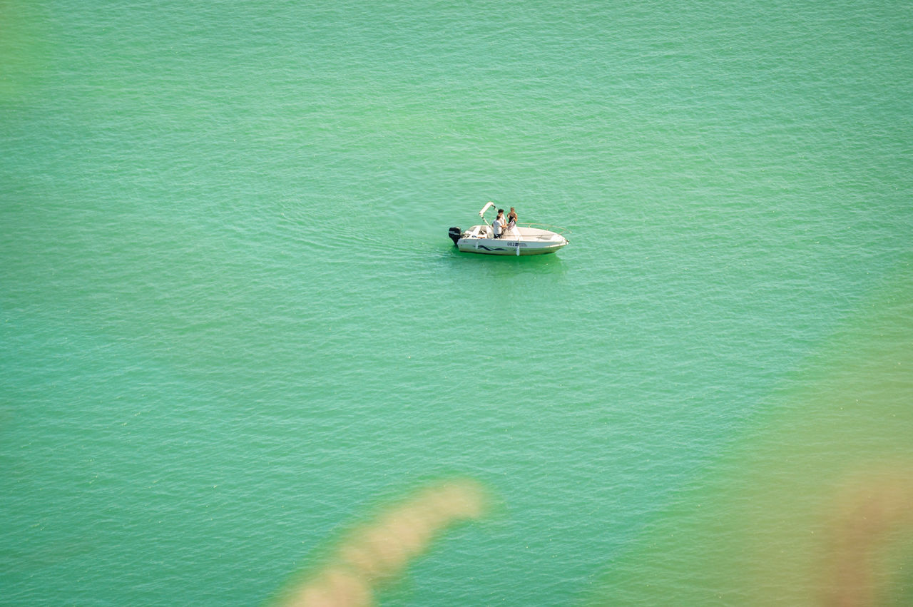 HIGH ANGLE VIEW OF PEOPLE ON SEA AGAINST GREEN WALL