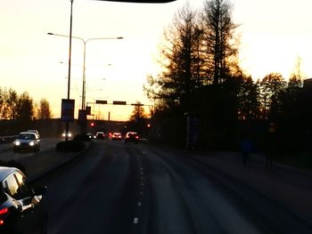 Cars on road against sky during sunset