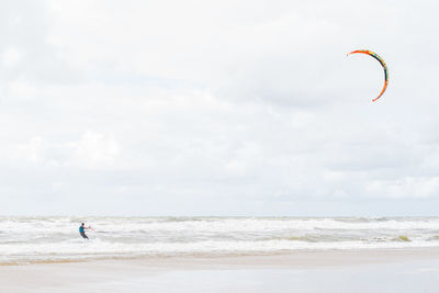 Man kiteboarding in sea against sky