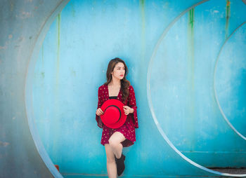 Portrait of woman standing against red wall