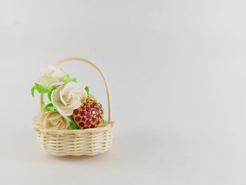 Close-up of roses in basket on table against white background