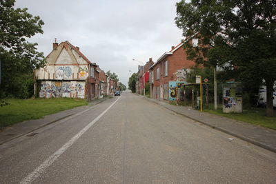 Road by buildings in city against sky