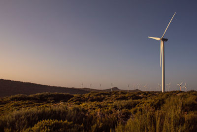 Wind turbines on field against clear sky