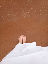 Low section of man standing on sand at beach