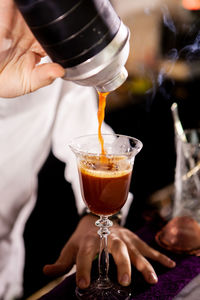 Midsection of man pouring drink on table