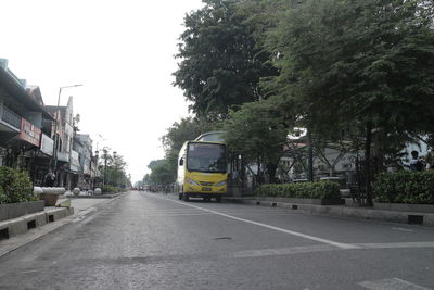 Road amidst trees in city against sky