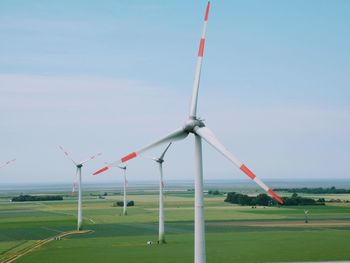 Wind turbines on field against sky