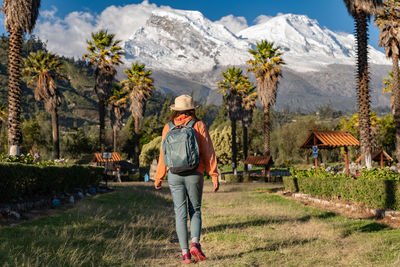 Tourist walks through the town named yungay with the snow-capped huascaran in the background.