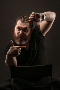 Portrait of man with arms raised against black background