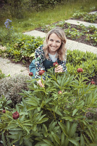 Portrait of young woman standing amidst plants