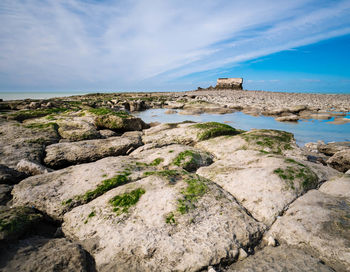 Rocks on shore by sea against sky