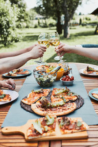 Friends making toast during summer picnic outdoor dinner in a home garden