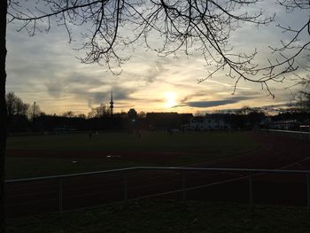 People on soccer field against sky during sunset