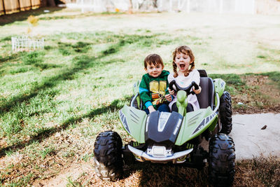 Young boy and girl sitting in powerwheels smiling during spring