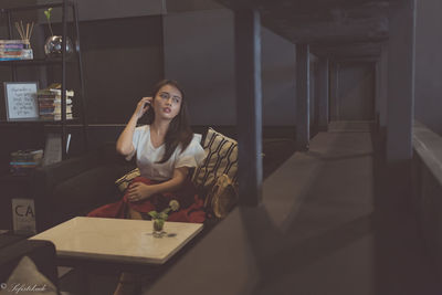 Young woman using phone while sitting on table