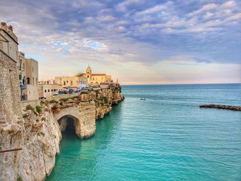 Buildings by sea against sky