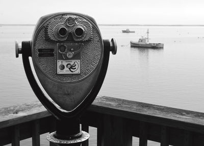 Close-up of coin-operated binoculars by sea against sky