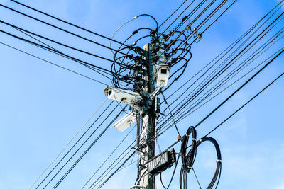 Low angle view of electricity pylon against blue sky