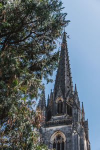 Low angle view of trees and building against sky