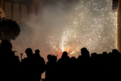 Silhouette people watching firework display at night