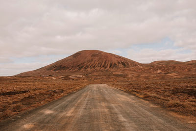 Road leading towards mountain against sky