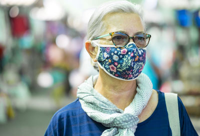 Senior woman wearing flu mask looking away while standing outdoors
