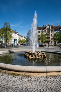 Fountain in city against sky