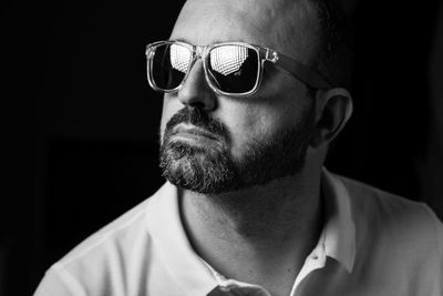 Close-up of man wearing sunglasses looking away against black background