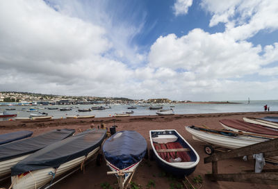 Panoramic view of boats moored on beach against sky