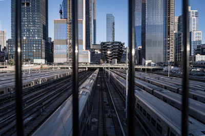 Railroad tracks by buildings in city against sky