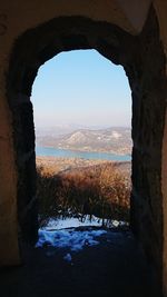 Scenic view of landscape against sky seen through arch window