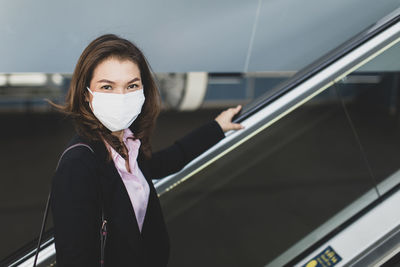 Portrait of young woman standing in car