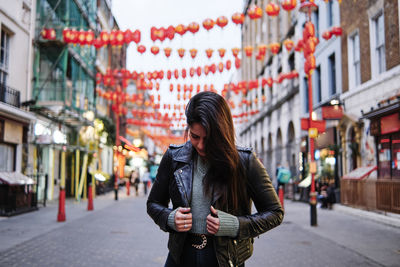 Full length of woman standing against buildings in city