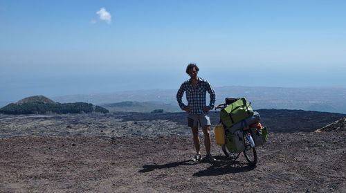 Men riding bicycle on mountain against sky