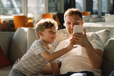 Young woman using mobile phone while sitting on sofa at home