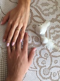 High angle view of couple hands wearing engagement rings on table