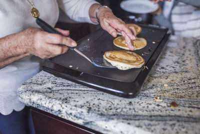 Close up of grandma cooking pancakes on a griddle