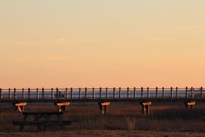 Chairs and table by sea against sky during sunset