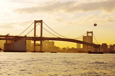 Rainbow bridge over river against sky during sunset