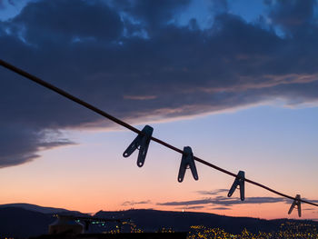 Low angle view of silhouette rope hanging against sky at sunset