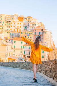 Full length of woman standing against buildings in city