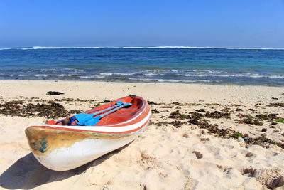 Boat moored on beach against sky