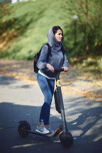 A girl in the park rides an electric scooter. sunny weather.