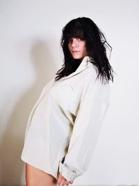 Portrait of young woman standing against white background