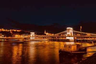 Illuminated bridge over river at night