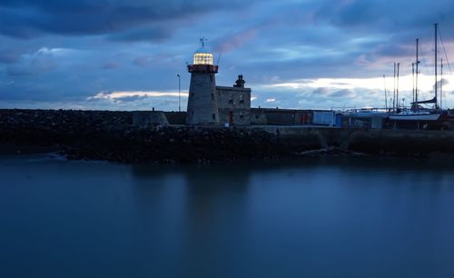 Lighthouse by sea against sky at dusk