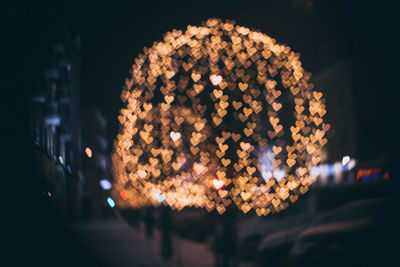 Defocused image of illuminated city against sky at night