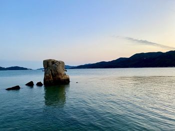 Rock formation in sea against blue sky